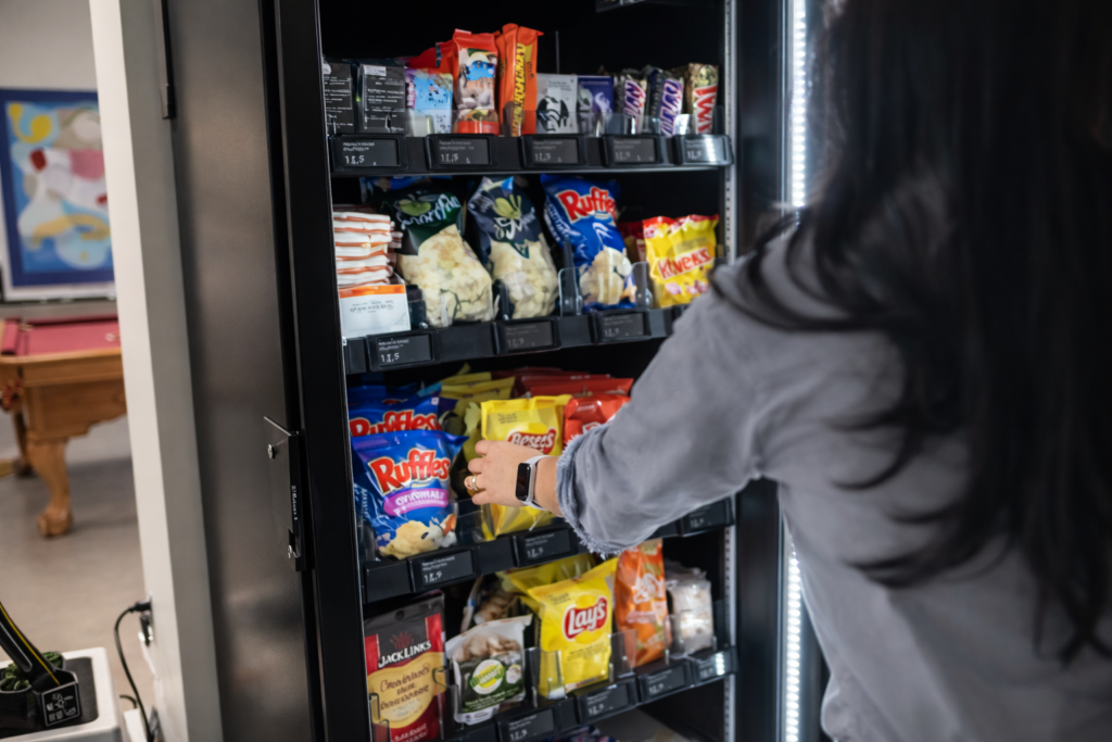 A woman is reaching into a vending machine to select a snack or drink.