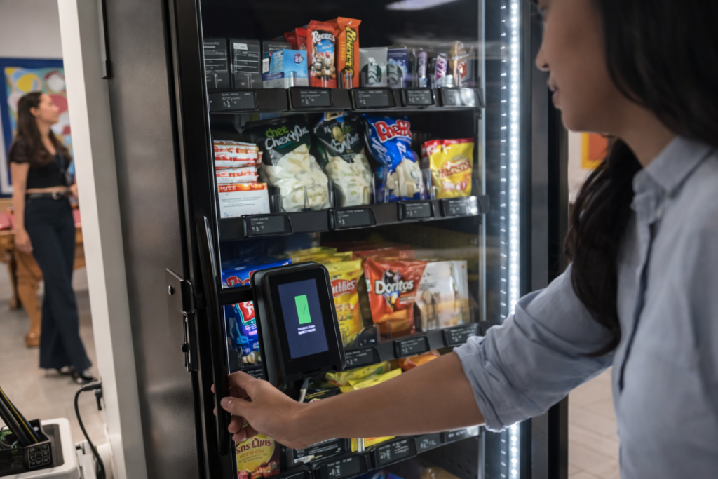 A woman interacts with a vending machine, choosing snacks for her purchase.