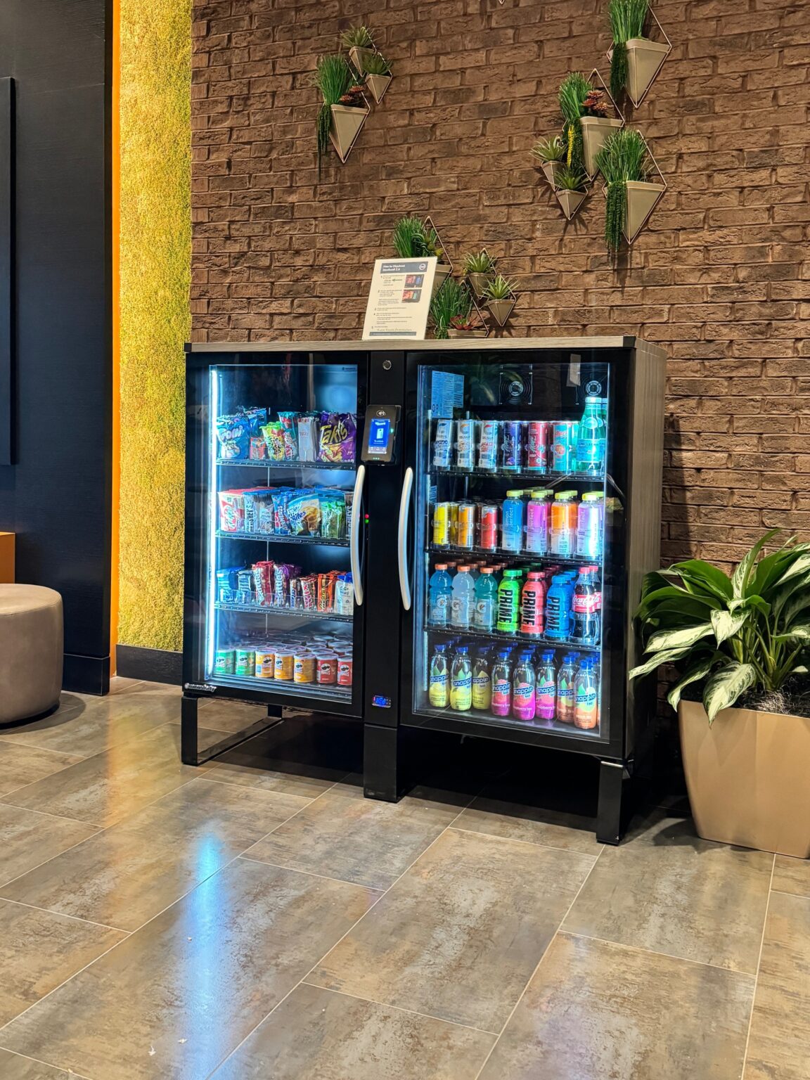 A vending machine displaying an assortment of beverages alongside decorative plants.